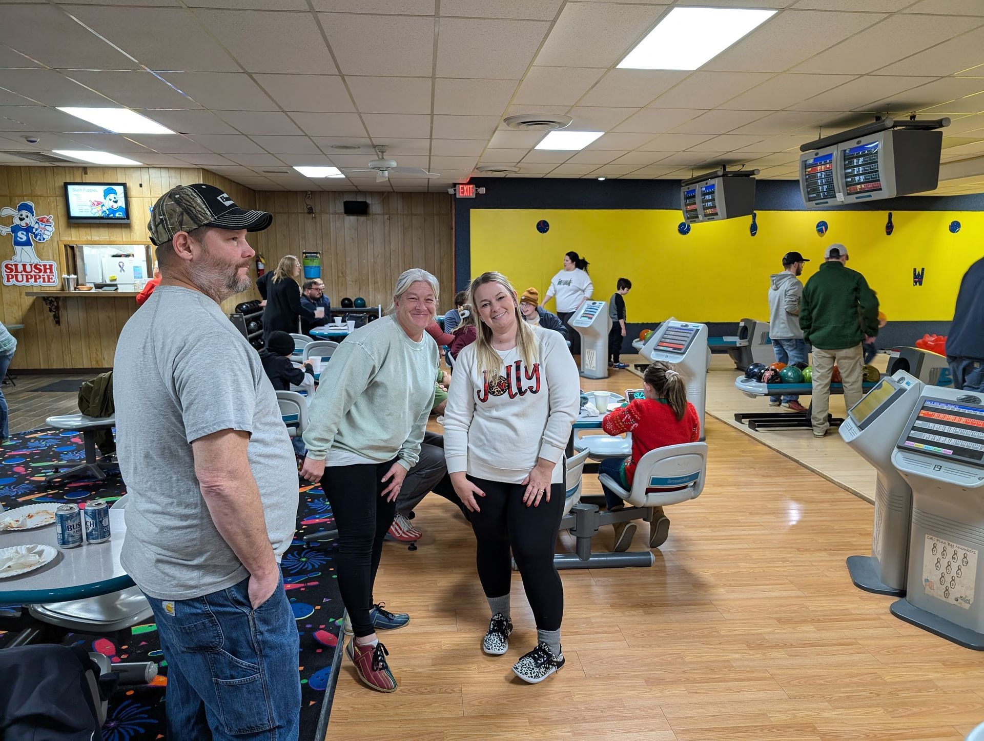 A group of people are standing in a bowling alley.