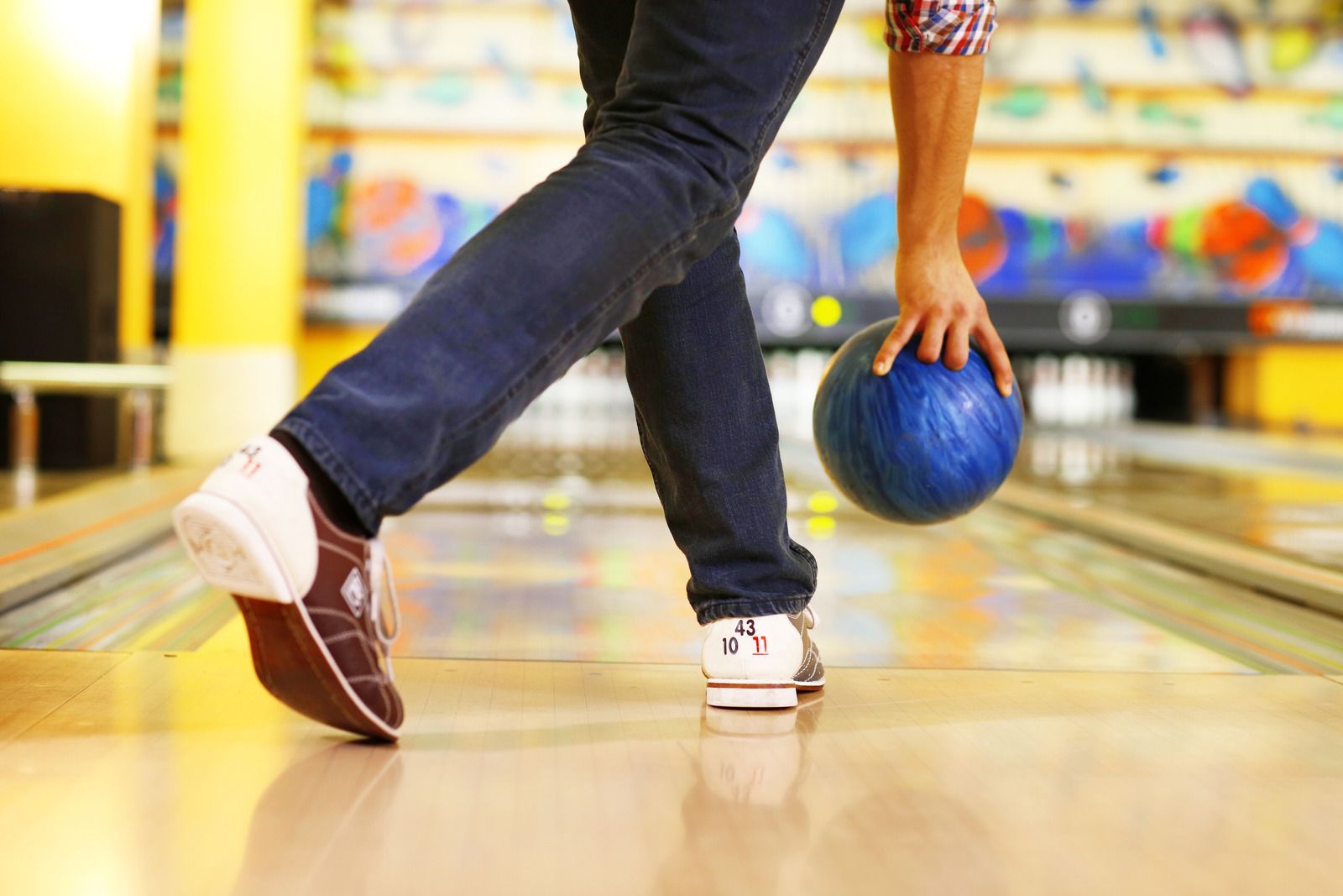 A person is holding a bowling ball on a bowling alley.