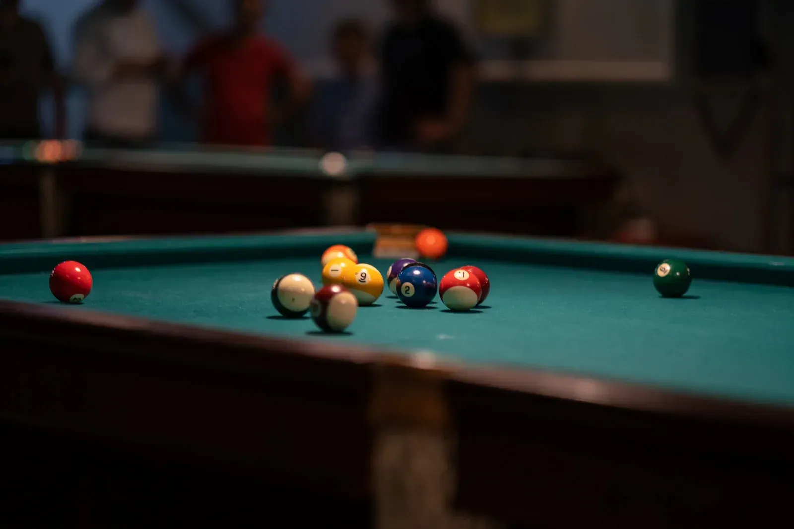 A pool table filled with pool balls in a pool hall.