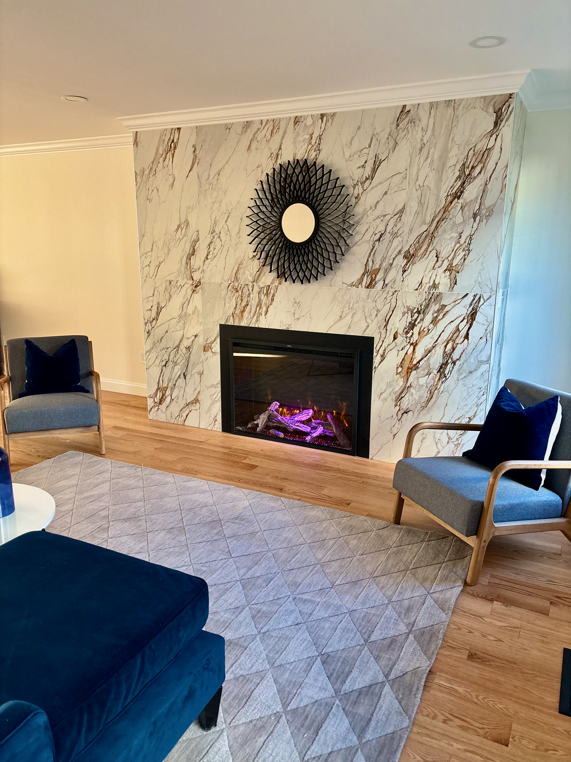 Living room with marble fireplace, hardwood floors, and two windows.