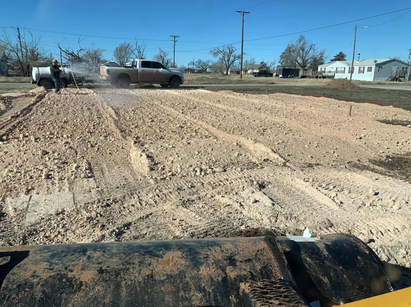 A skid-steer leveling dirt in a field, a truck spraying water, and a residential street.