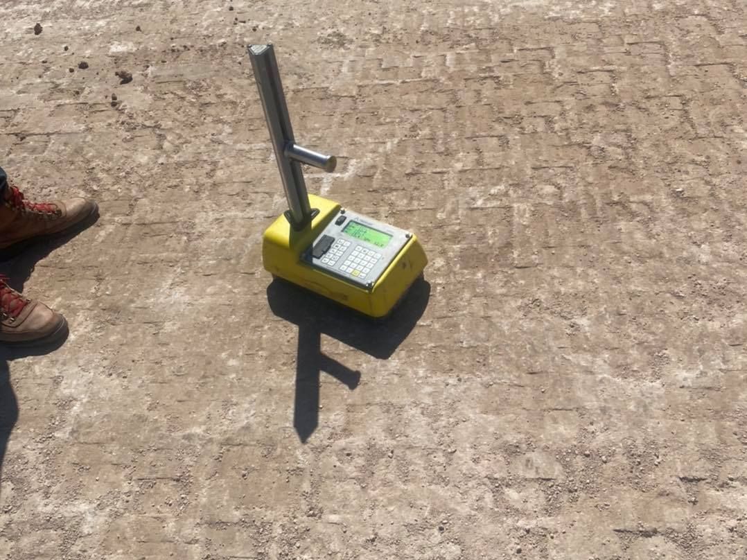 Yellow device with handle on a rough surface, measuring something.