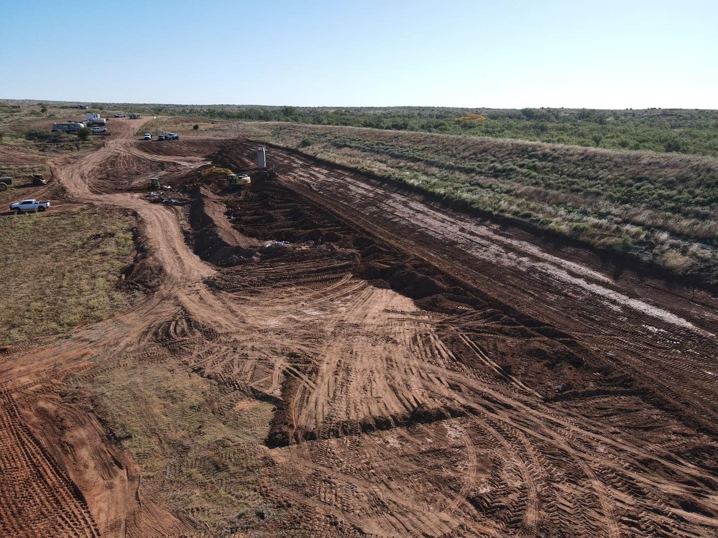 Dirt construction site with tracks and mounds of dirt.