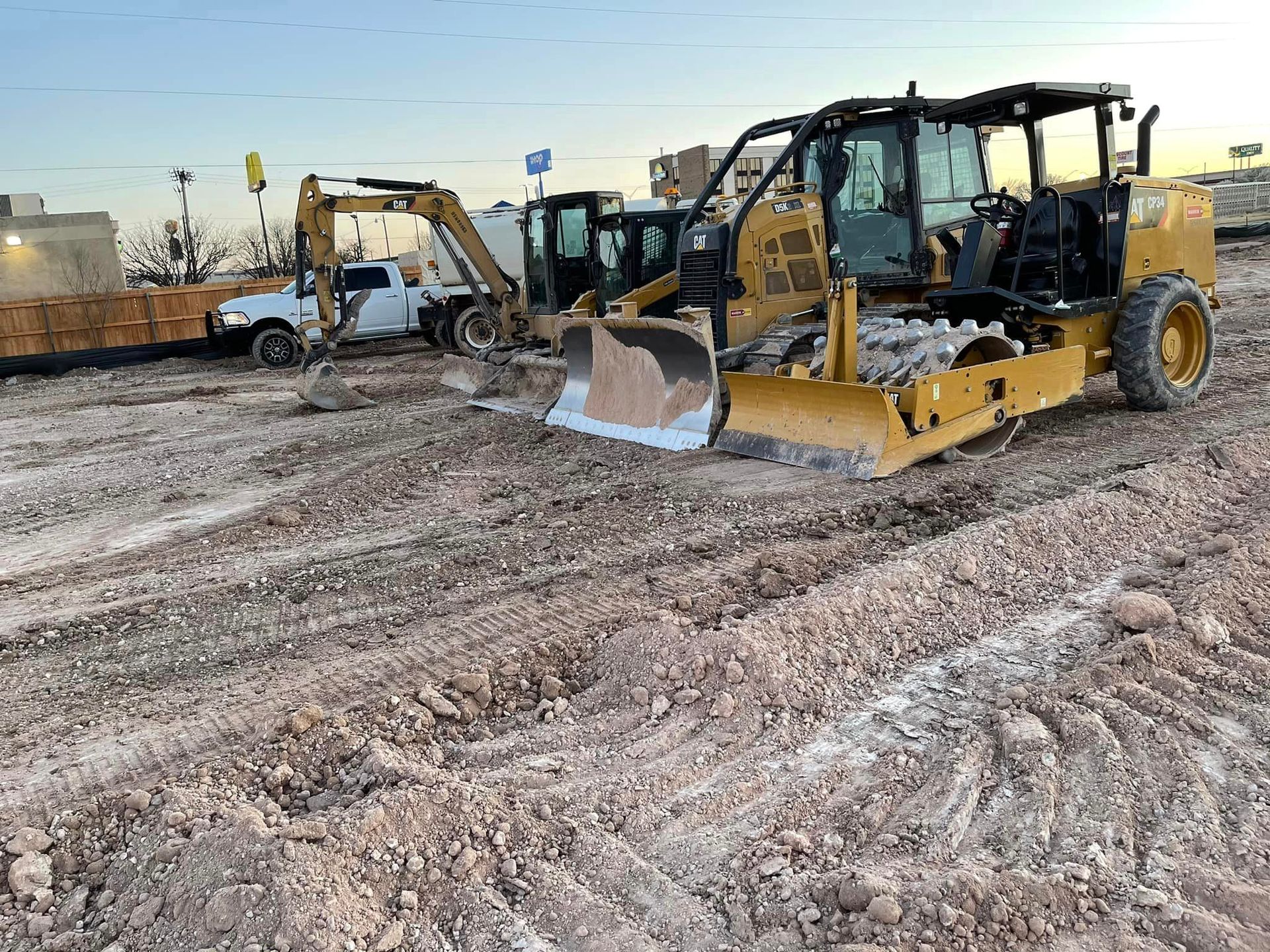 Construction site with yellow bulldozer, excavator, and truck on dirt.