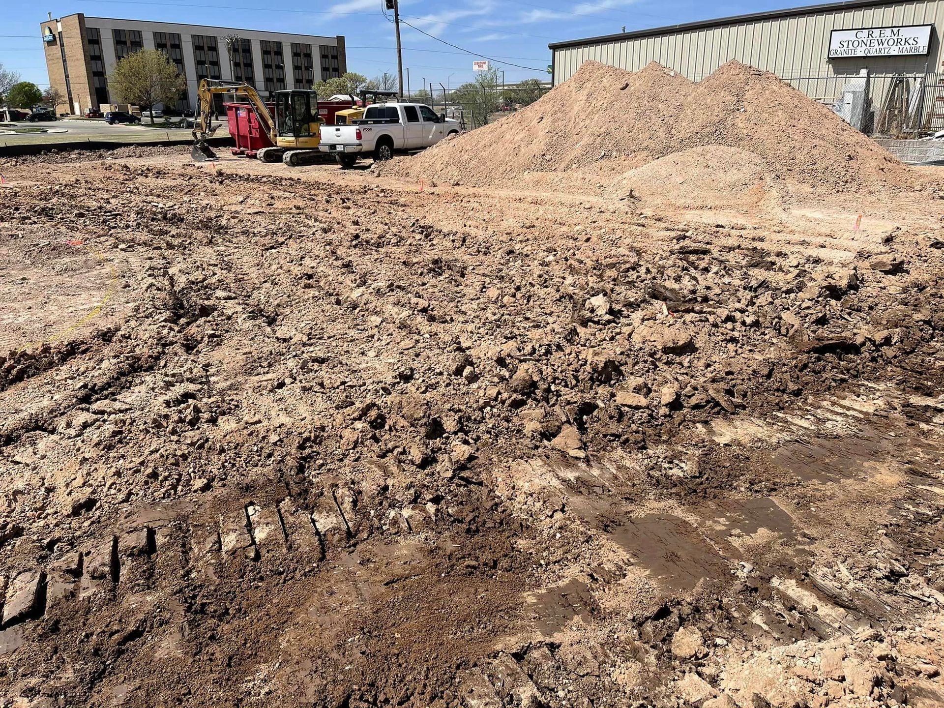 Construction site with a pile of dirt and vehicles in the background.