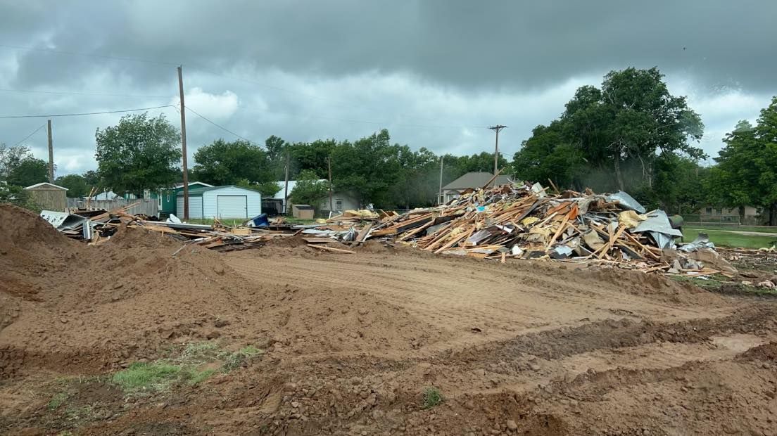 Pile of debris and dirt at a demolition site under a cloudy sky.