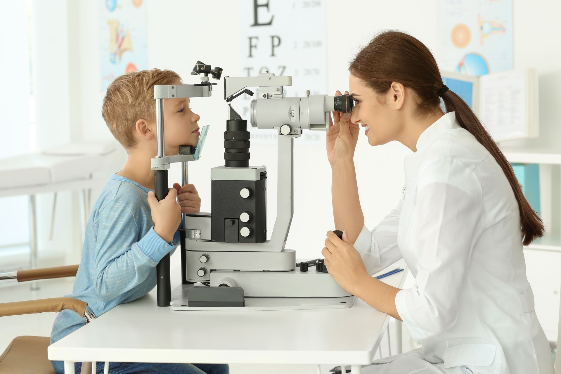 Doctor examining a child’s eyes with an eye chart and vision testing equipment