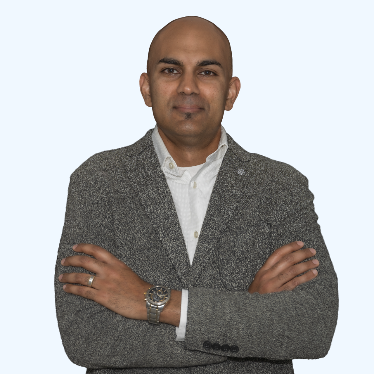 Man in a gray blazer and white shirt standing with arms crossed against a light background
