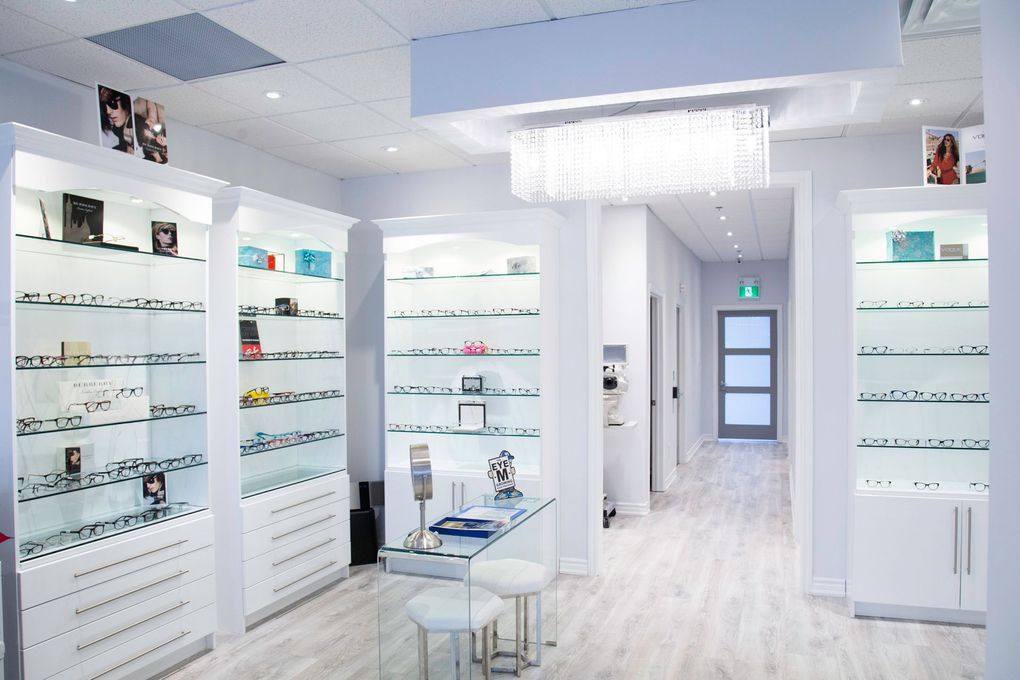 Bright white eyewear boutique with glasses displayed on wall shelves and a small display table.
