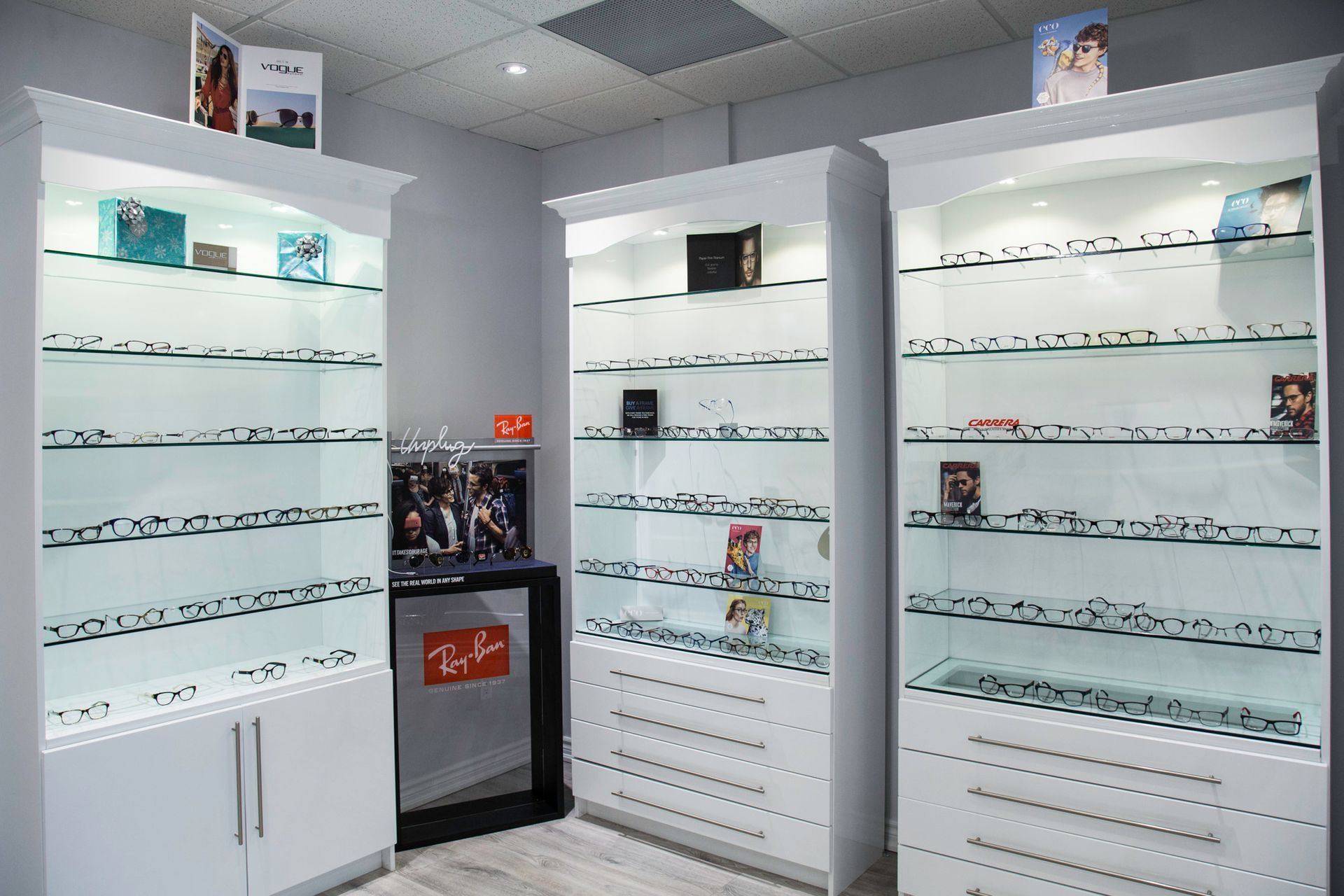 Eyeglasses displayed on white shelves in a bright optical shop interior