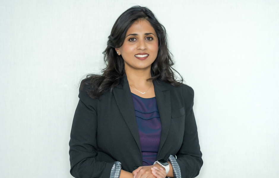 Woman in a dark blazer smiling against a light background