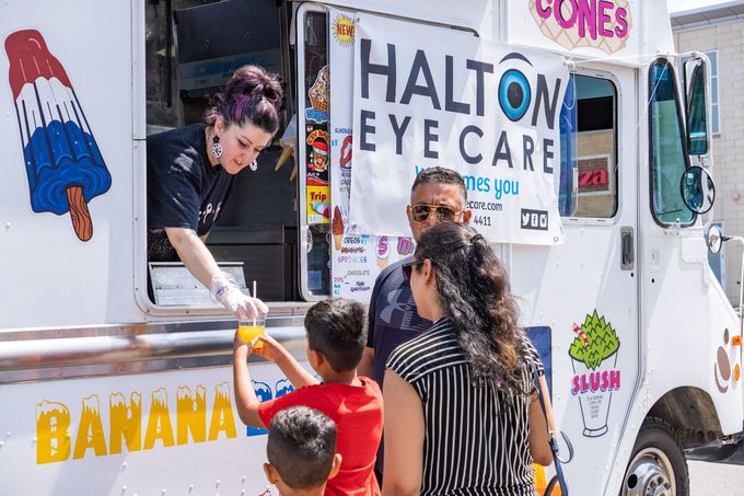 Eye care van serving banana popsicles to children in a sunny outdoor setting