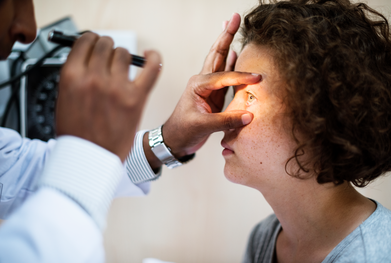 Eye exam with doctor using an otoscope on a patient in a clinical setting