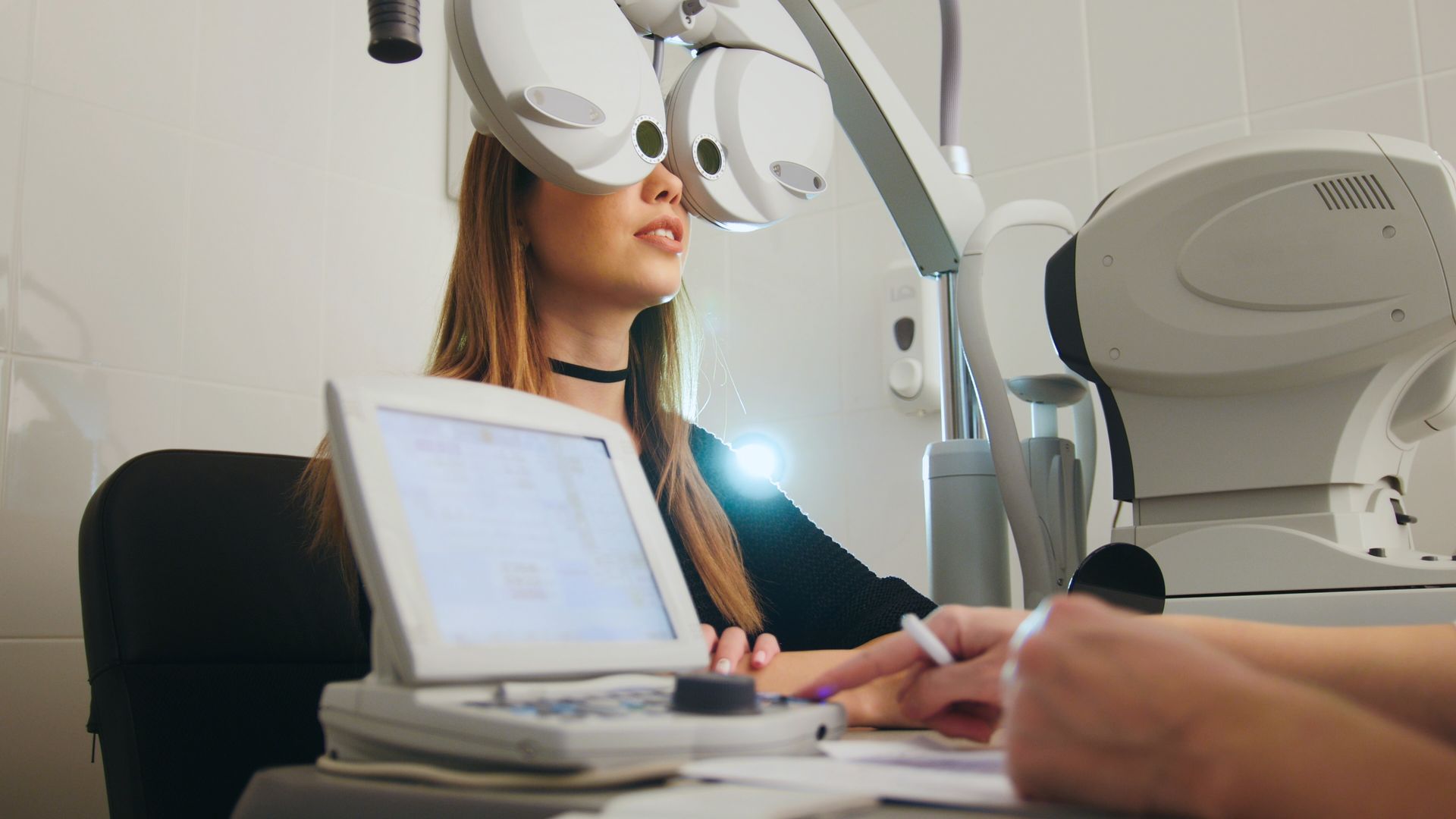 Patient during an eye exam with an optometrist using diagnostic equipment in a clinic