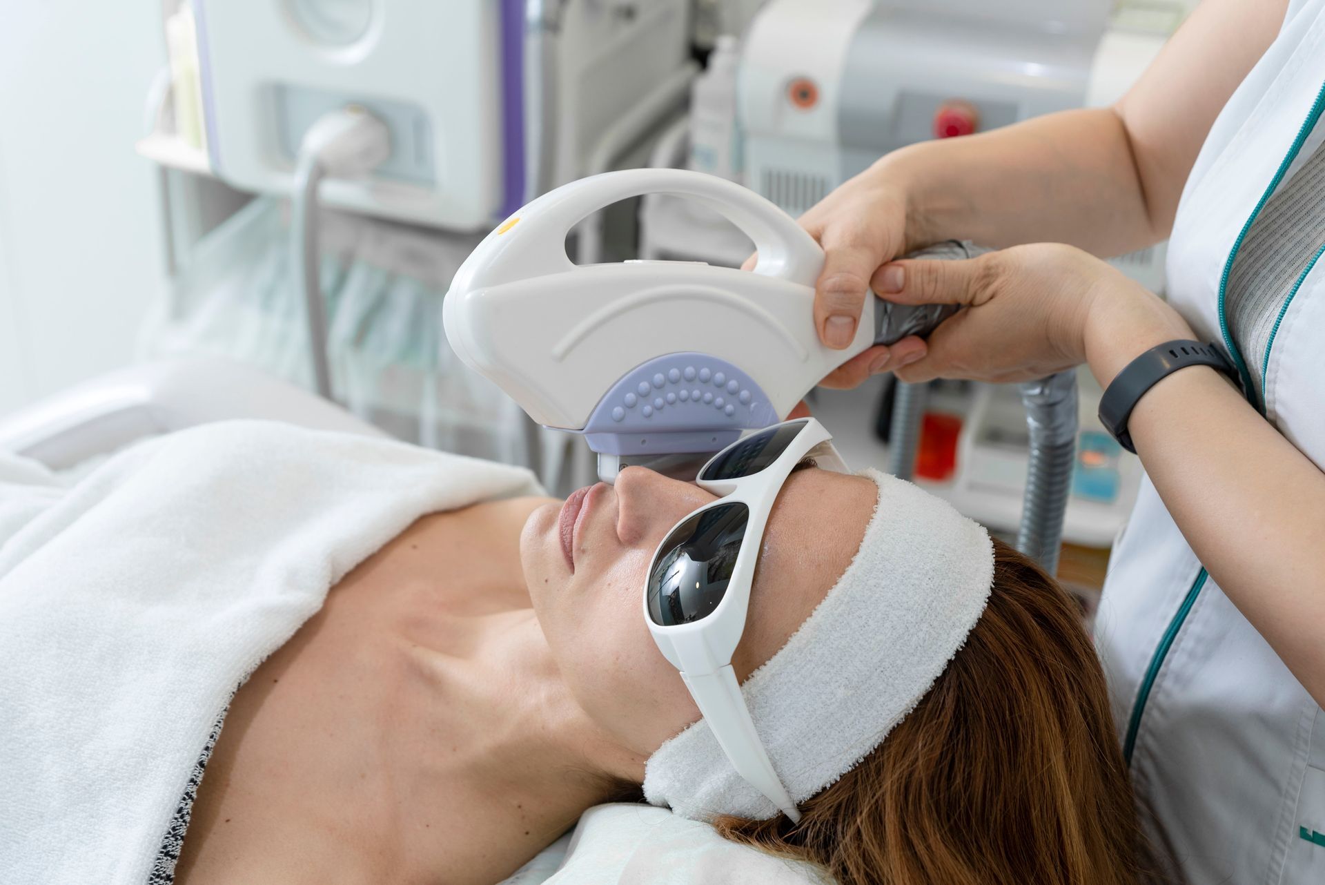 Person receiving a facial treatment with a handheld device in a bright spa room