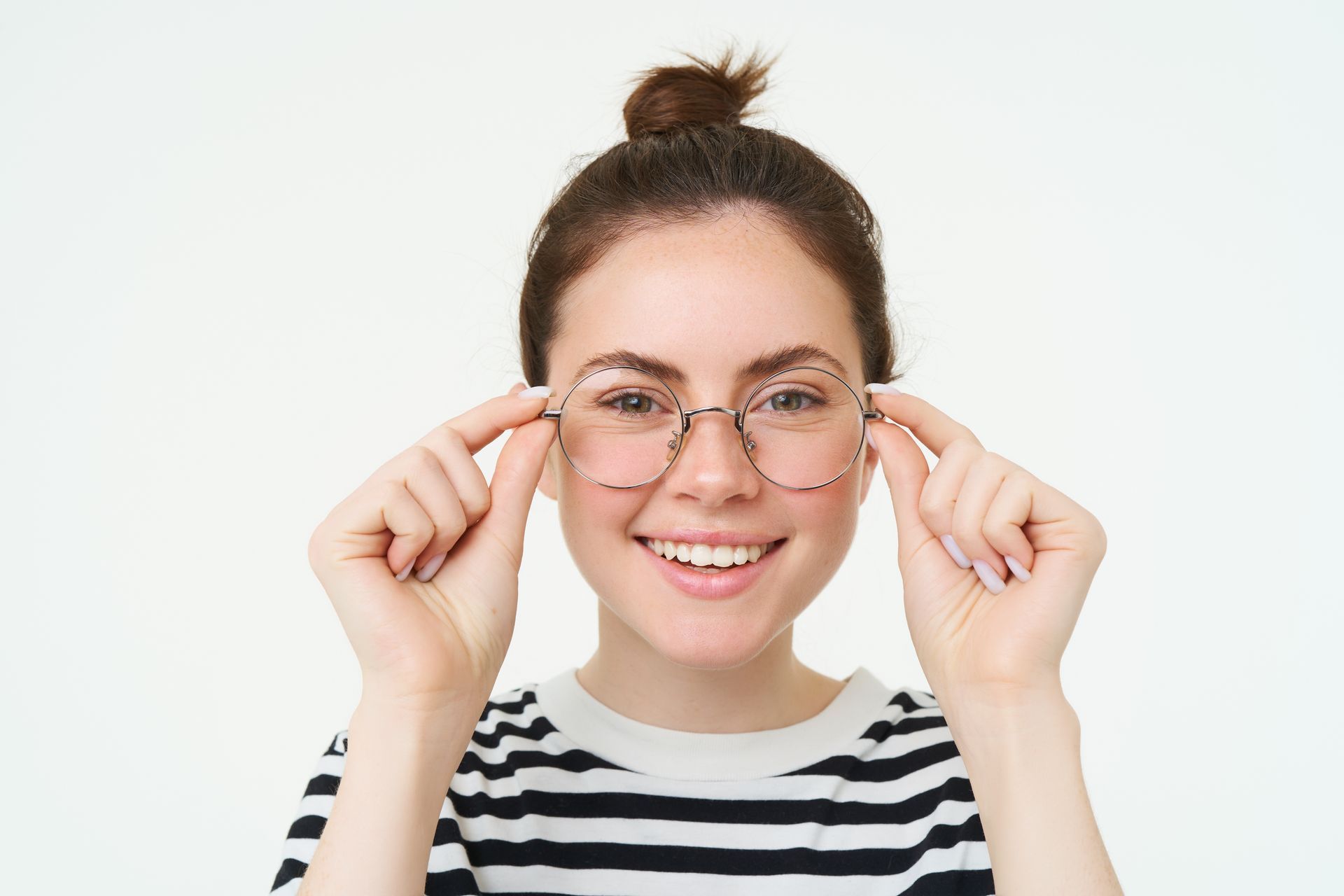 Smiling person adjusting round glasses, wearing a black-and-white striped shirt against a white background