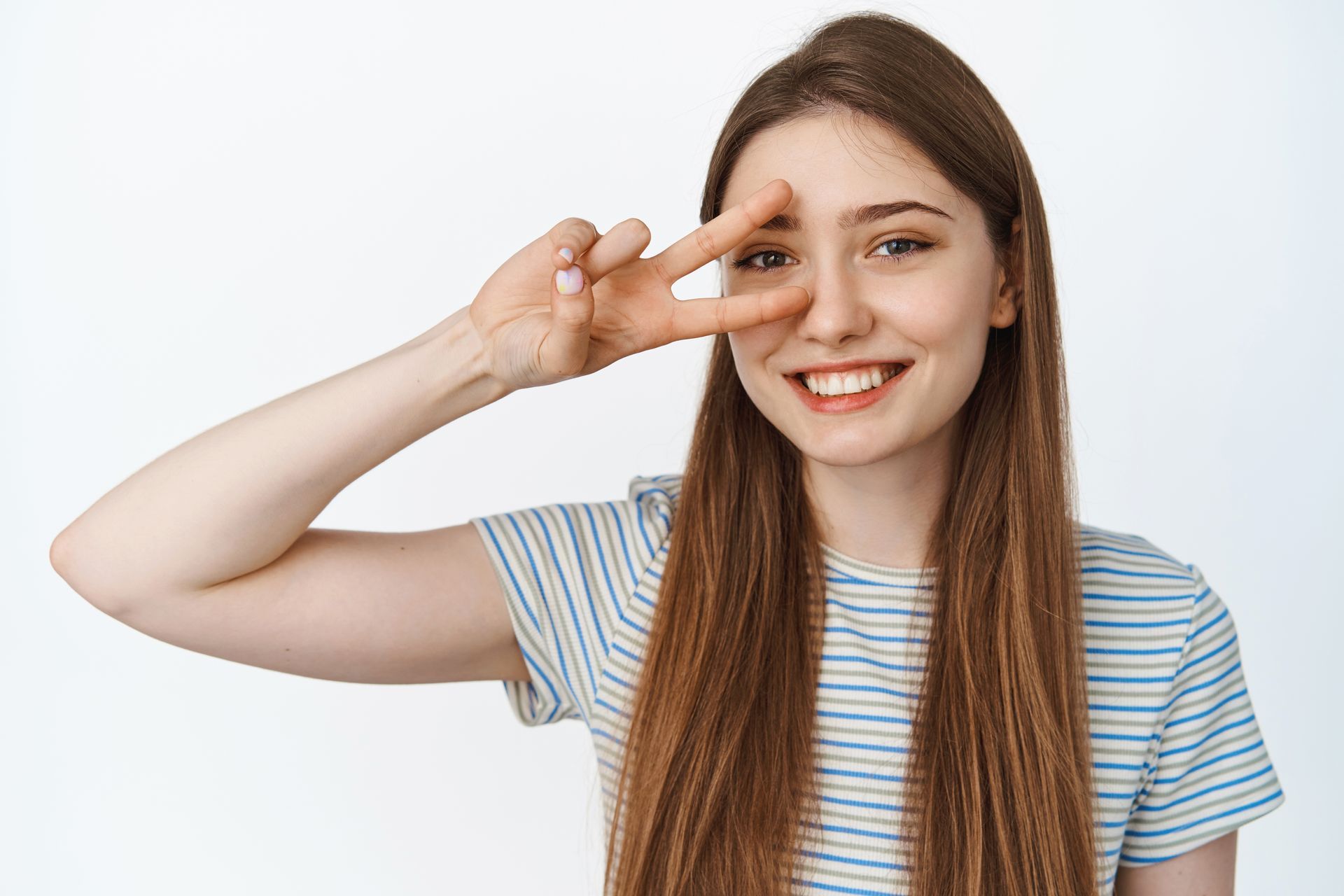 Smiling person in a striped shirt making a peace sign against a white background