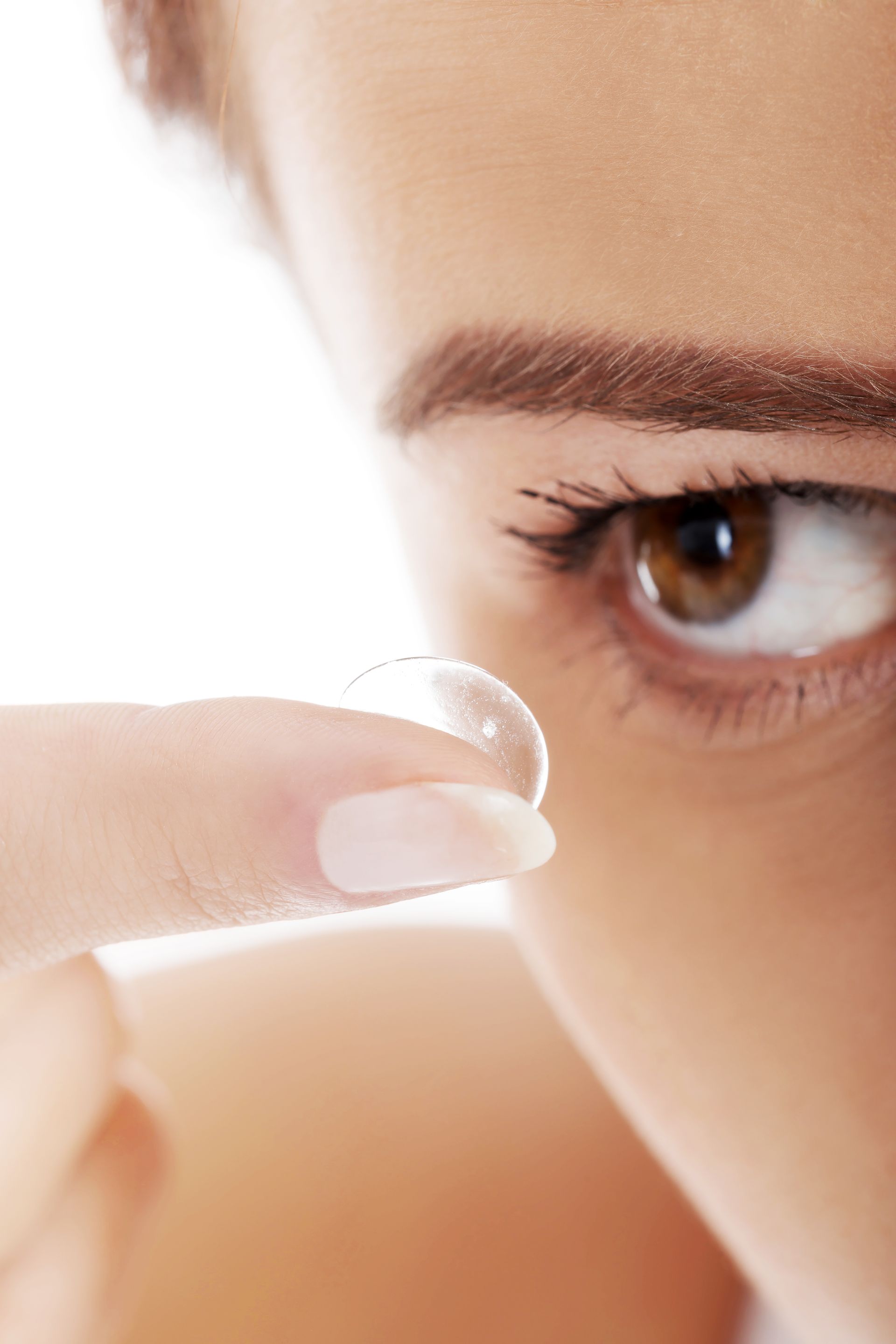 Close-up of a person holding a contact lens near their eye.