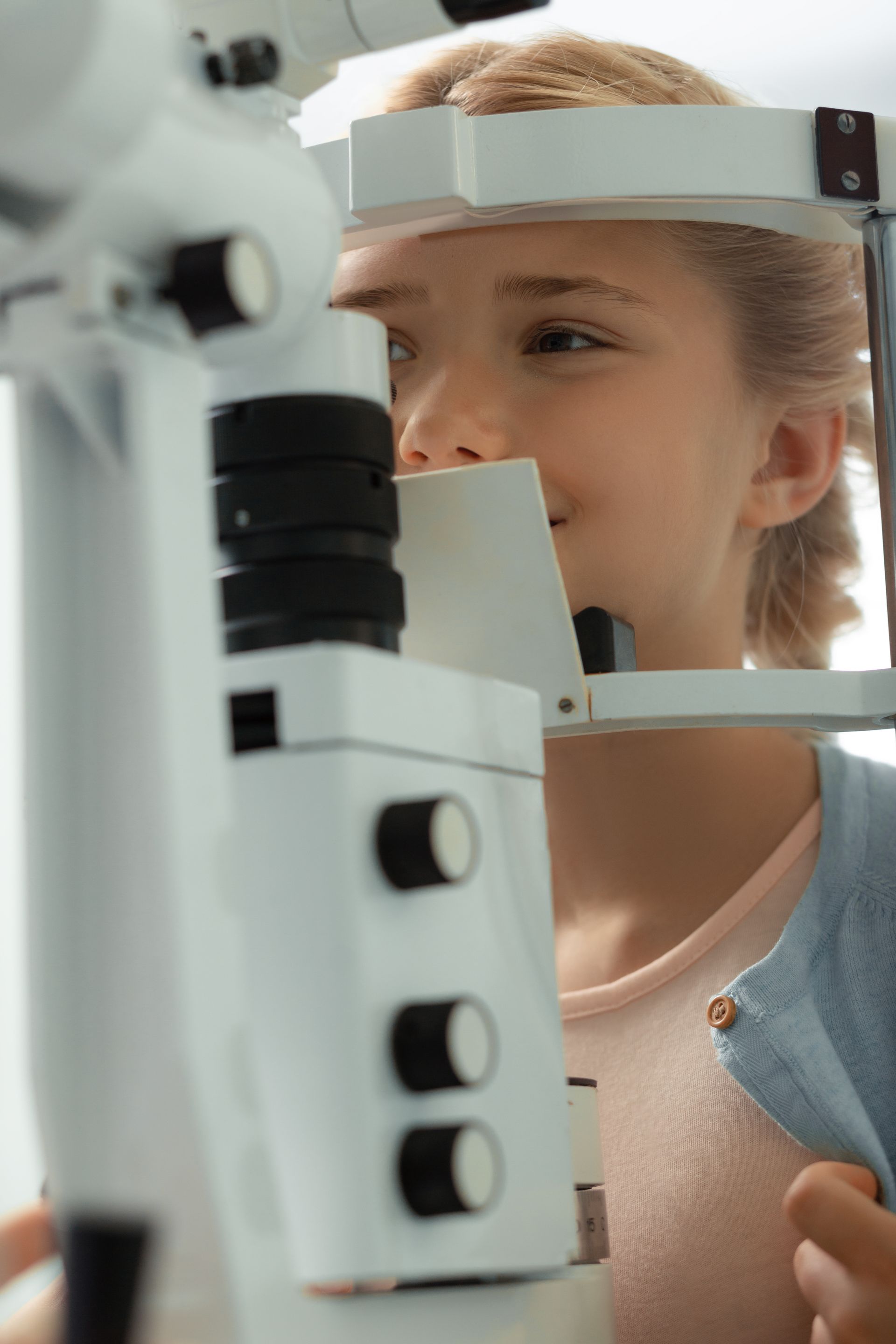 Child looking through an eye exam machine in a clinic