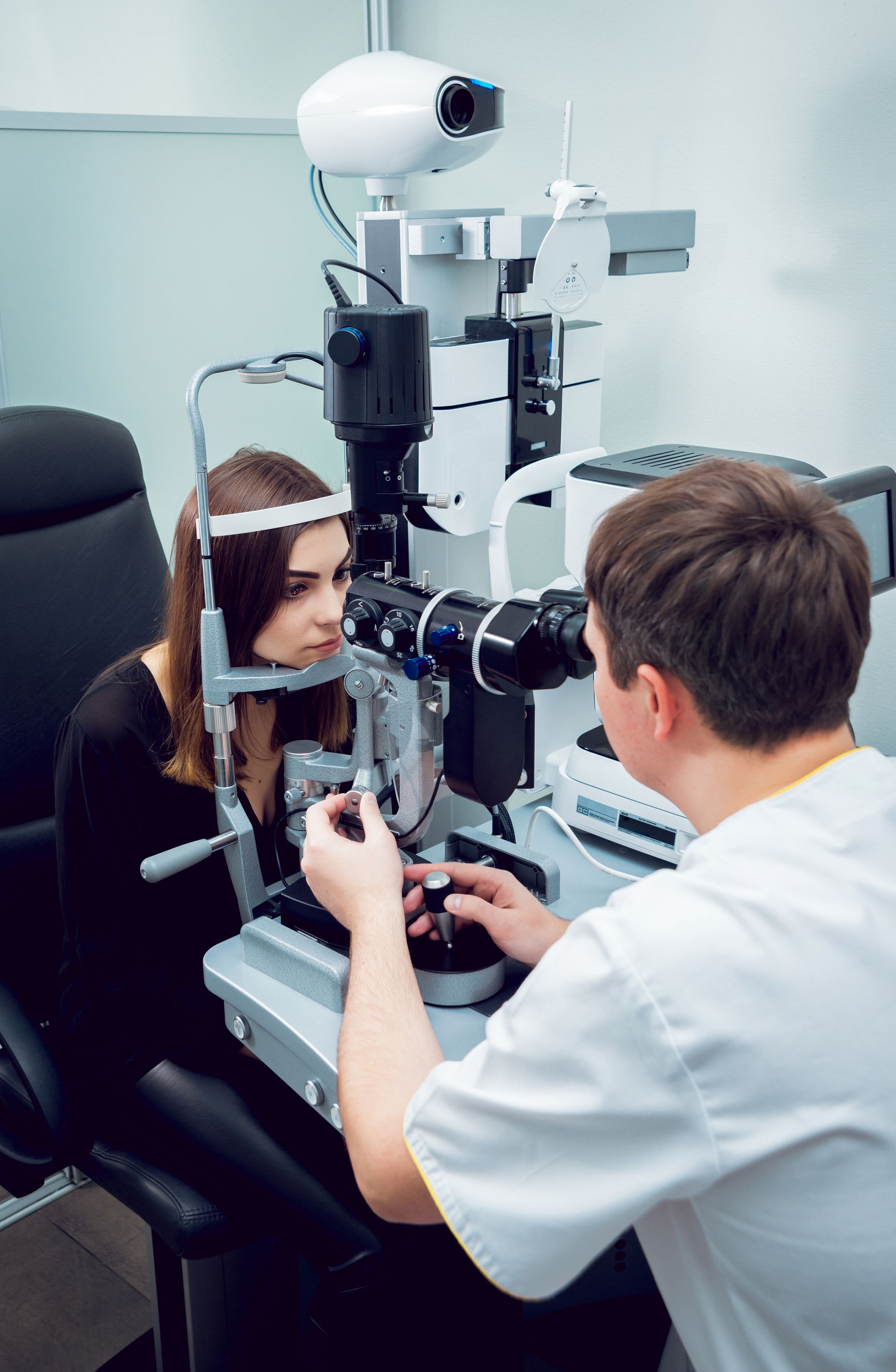 Eye exam with optometrist examining a patient at a slit lamp in a clinic