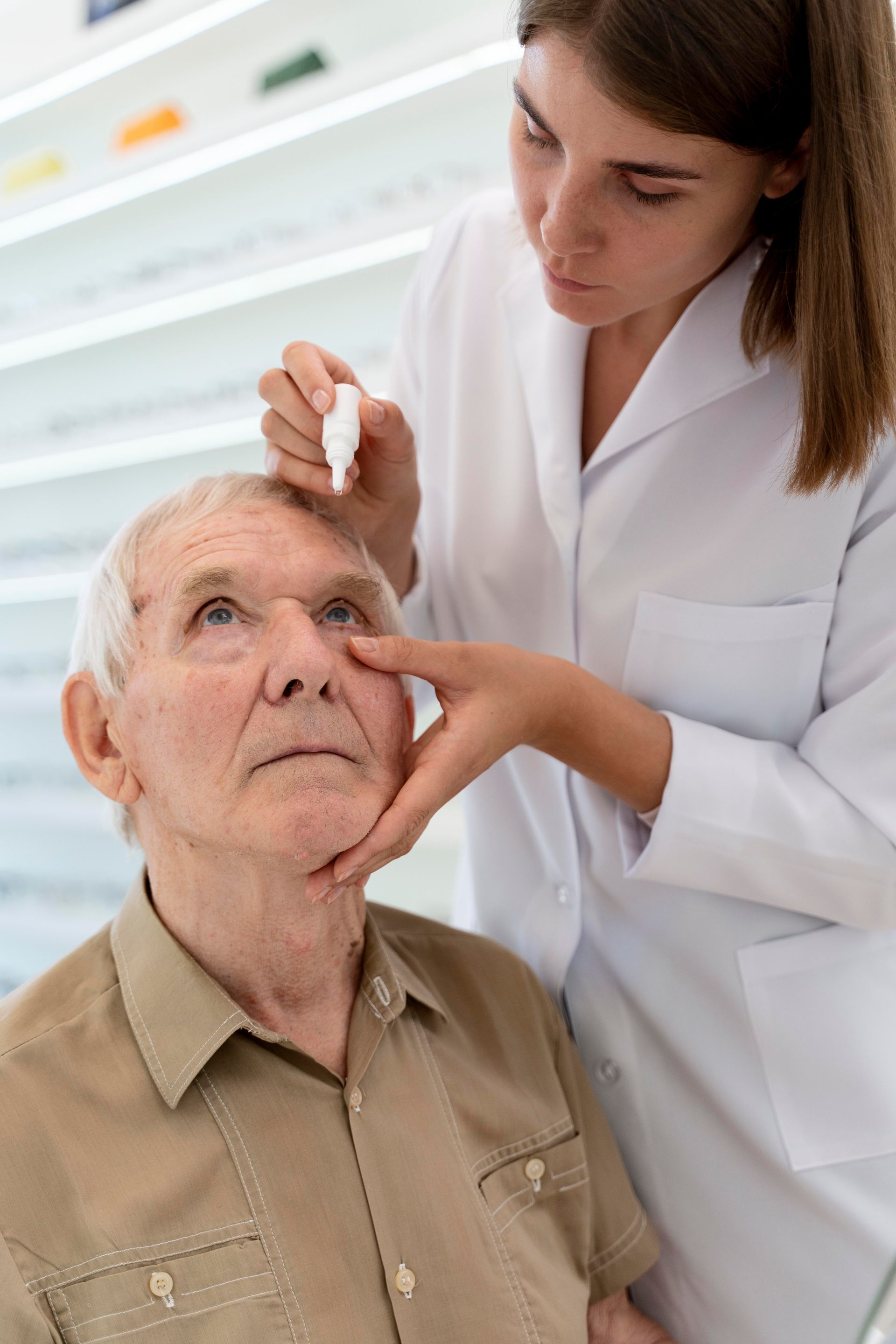 Nurse examining an elderly man's eye in a bright clinic