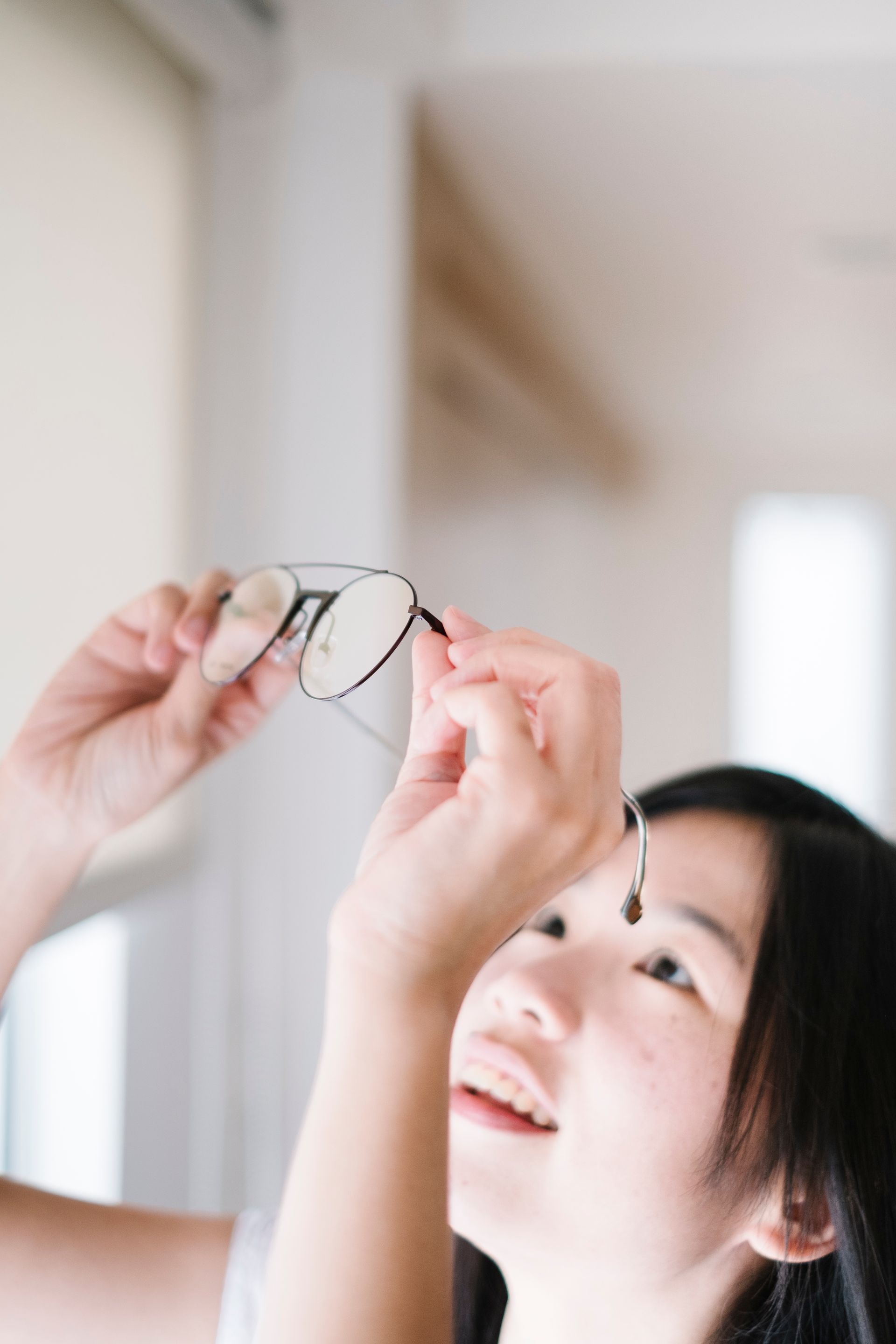 A woman is holding a pair of glasses in her hand.