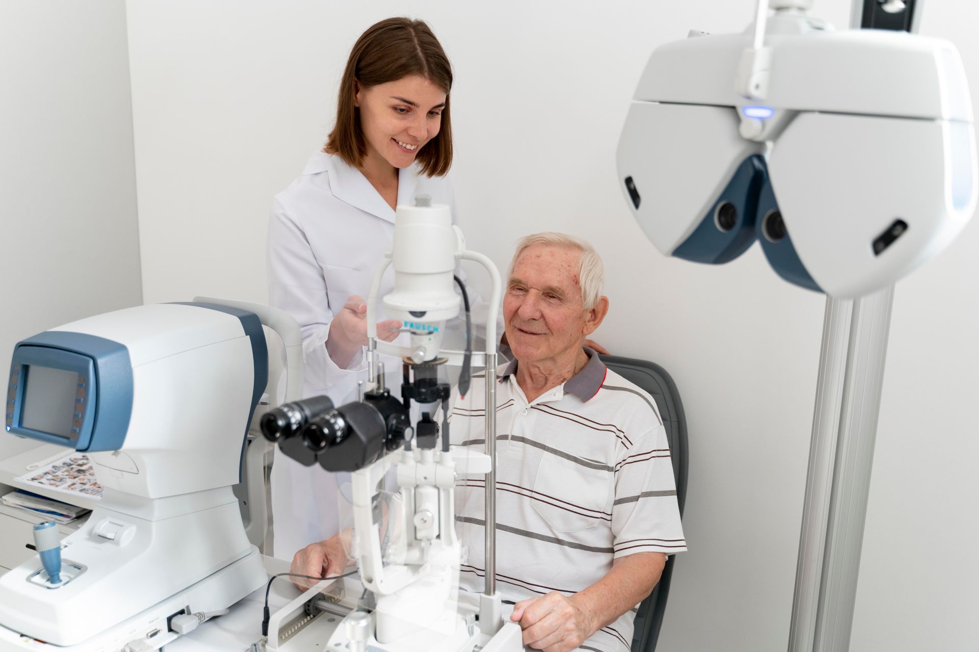 Eye exam in a clinic: technician using a slit lamp on a seated patient, with diagnostic equipment nearby.