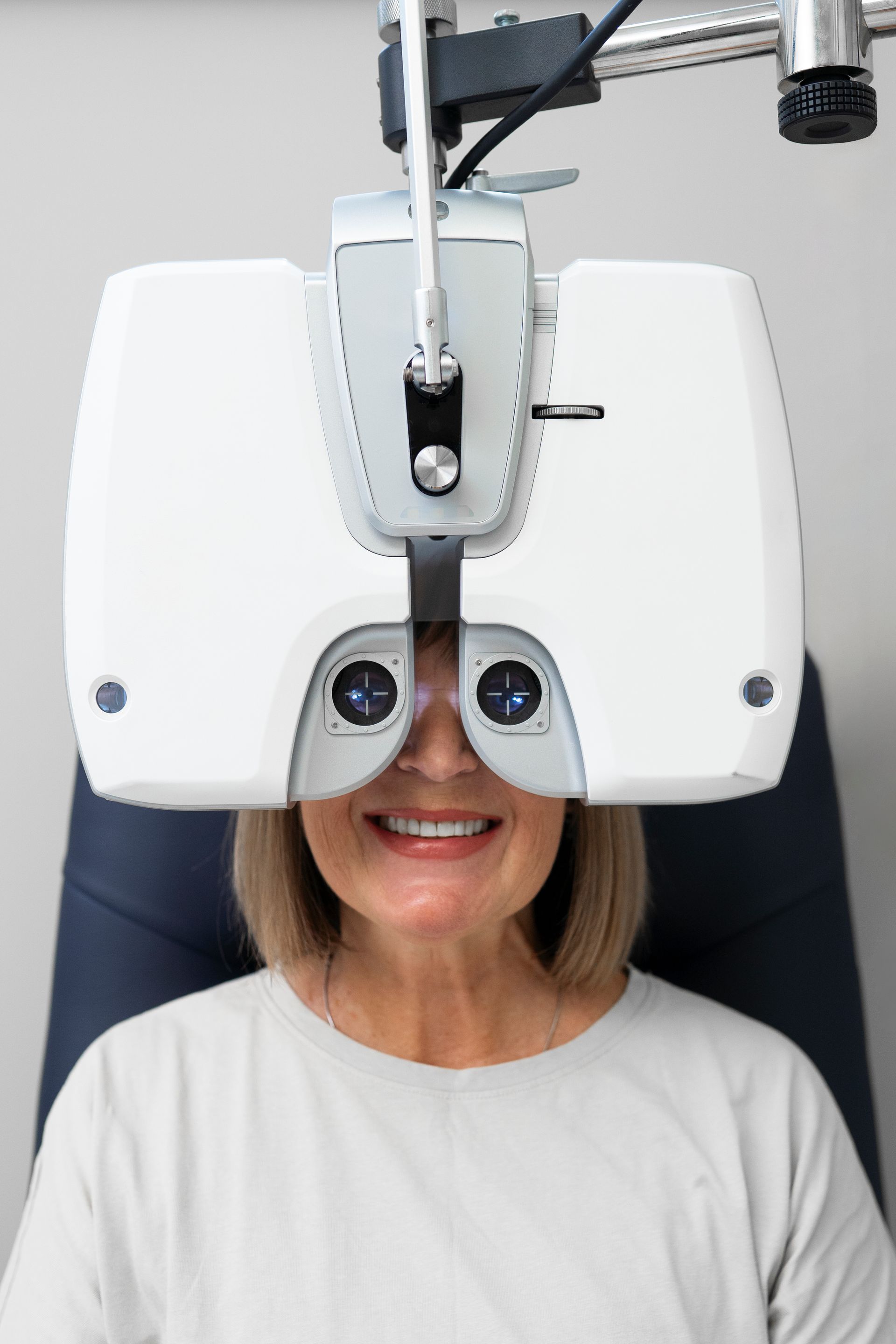 Person smiling during an eye exam with a white phoropter in a clinic