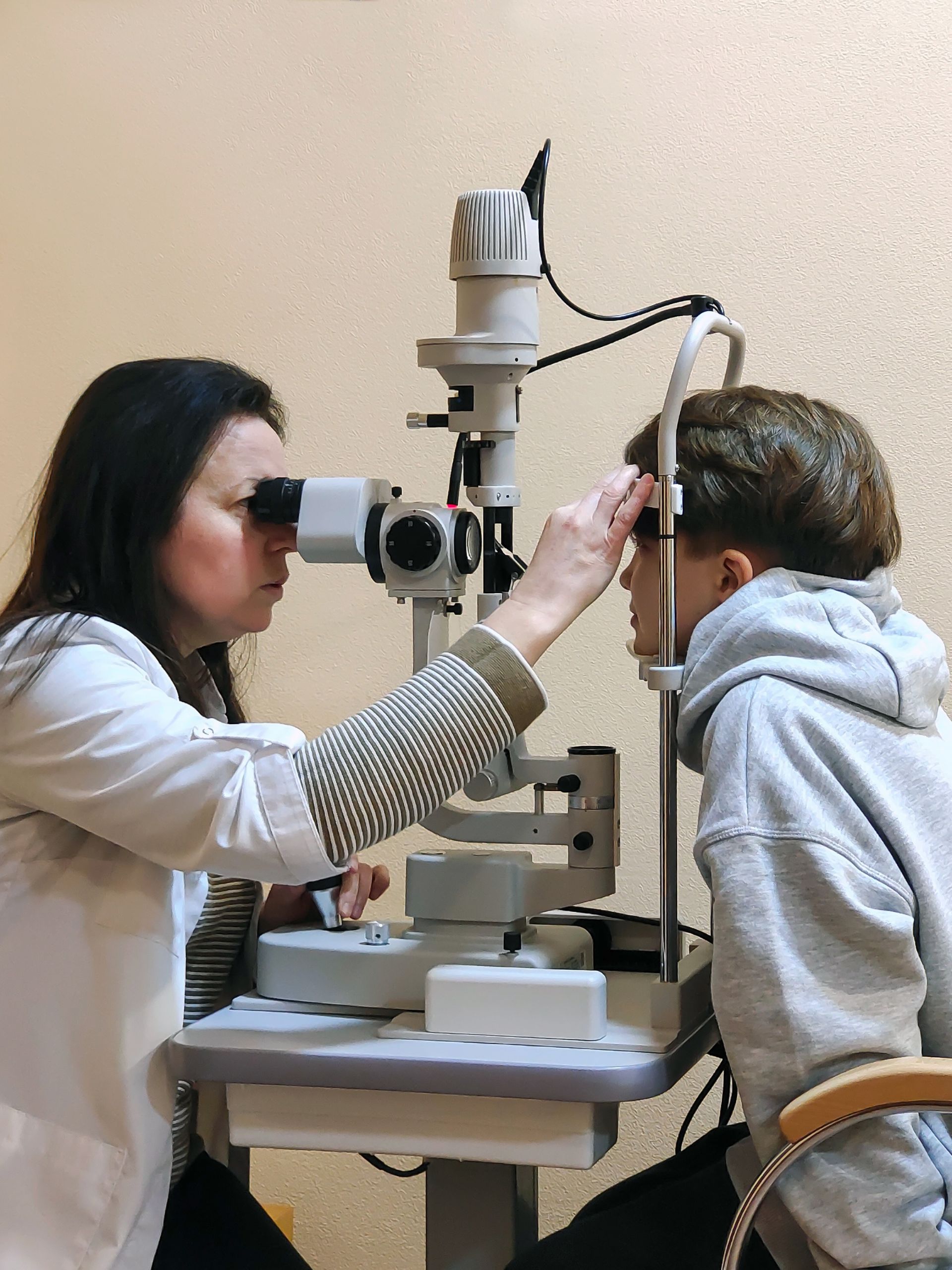 Eye doctor examining a patient with a slit lamp microscope in a clinic