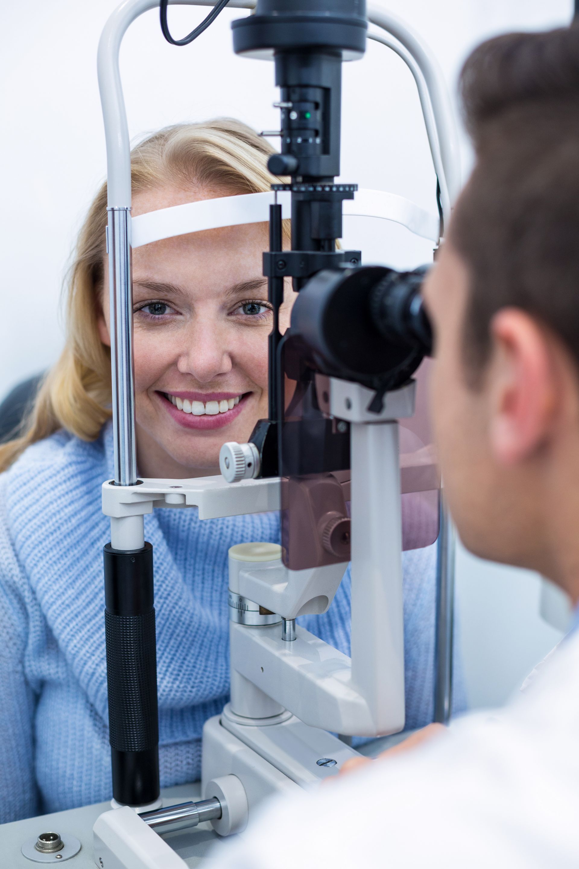 Patient being examined with a slit lamp by an eye doctor in a clinic, smiling during the eye exam