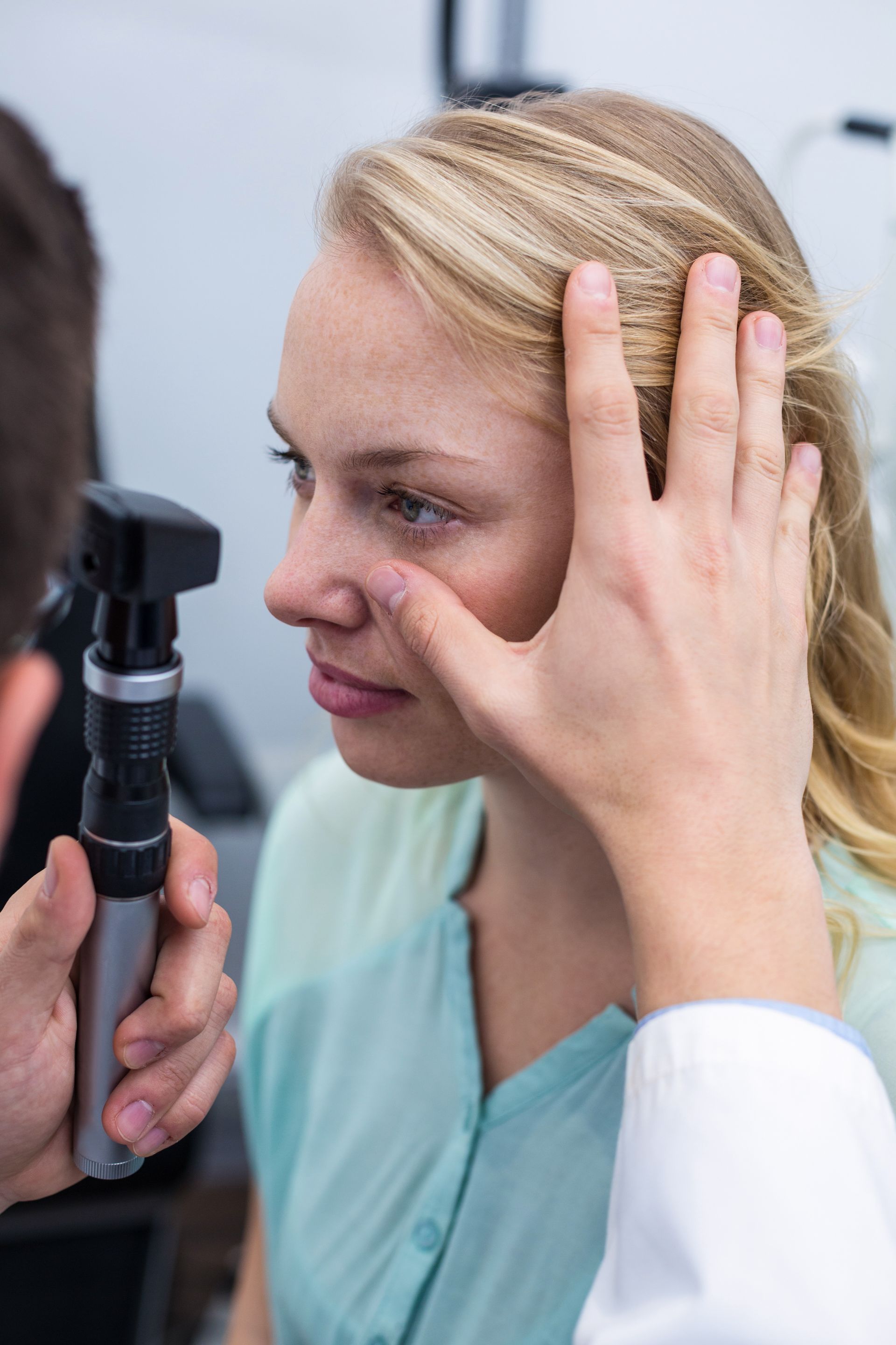 Doctor examining a patient’s eye with an ophthalmoscope during a clinic exam