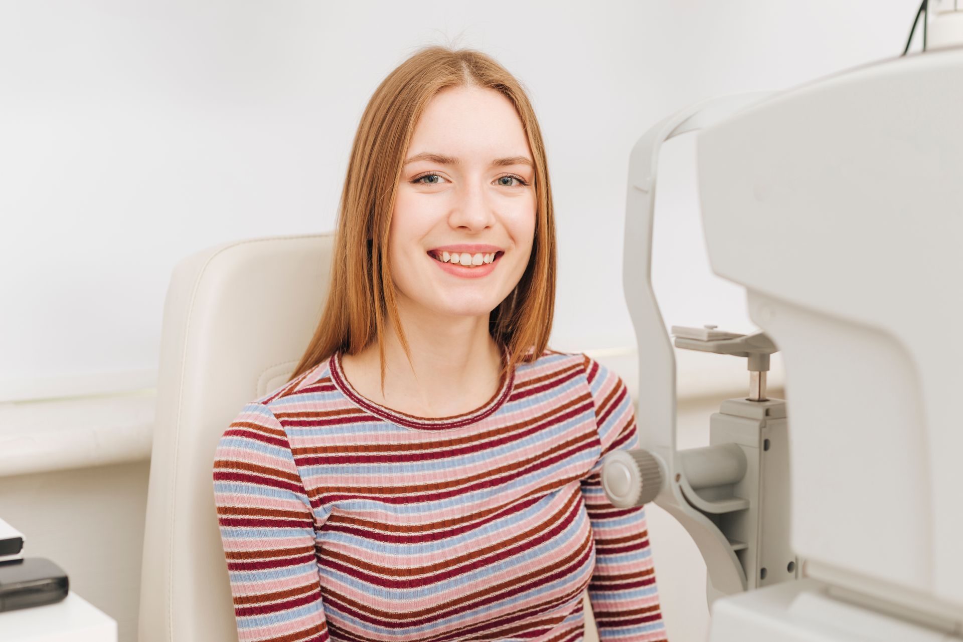 Smiling person seated in a dental chair in a bright clinic room