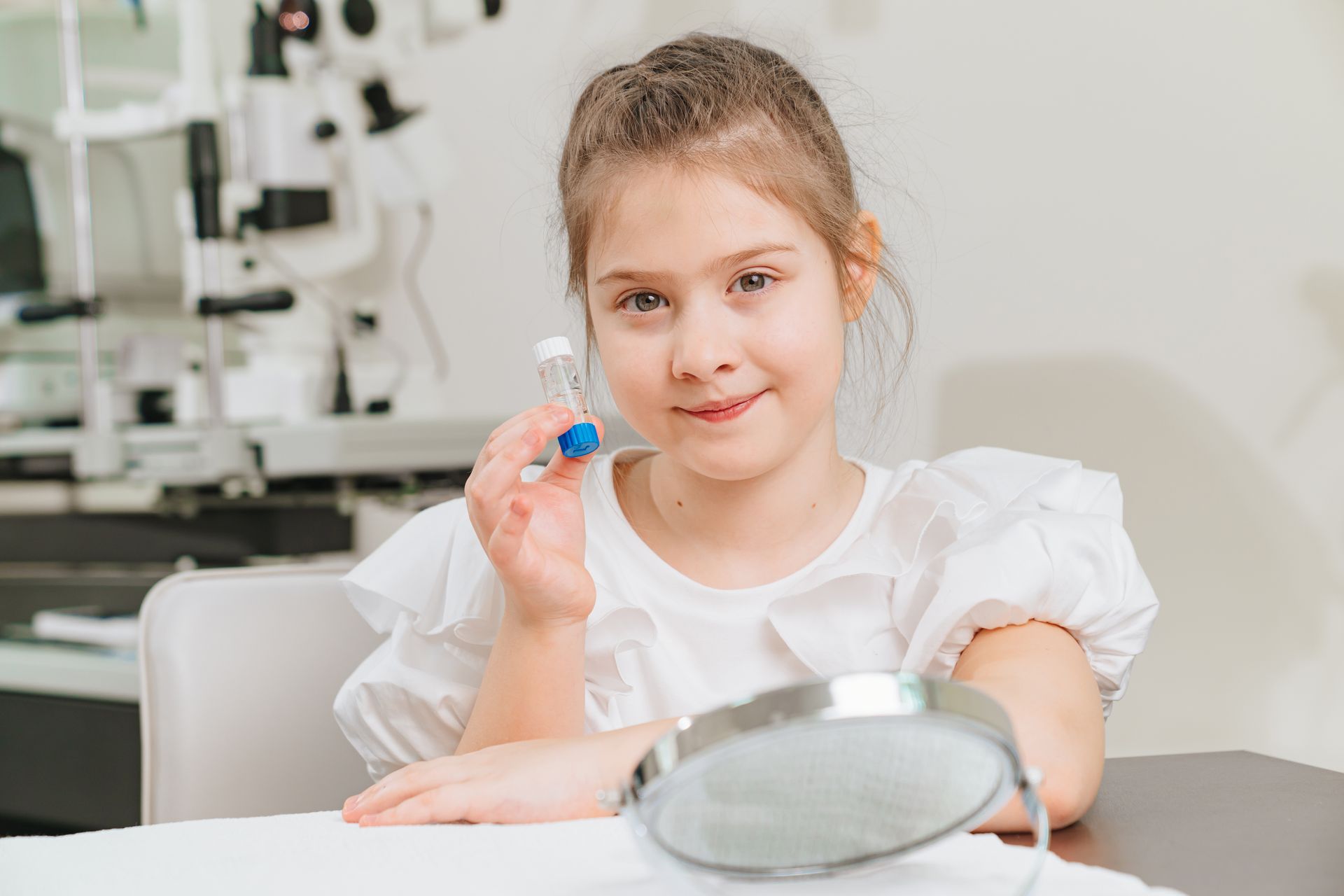 Girl at a desk holding a blue dental model, with a dental mirror in front of her.