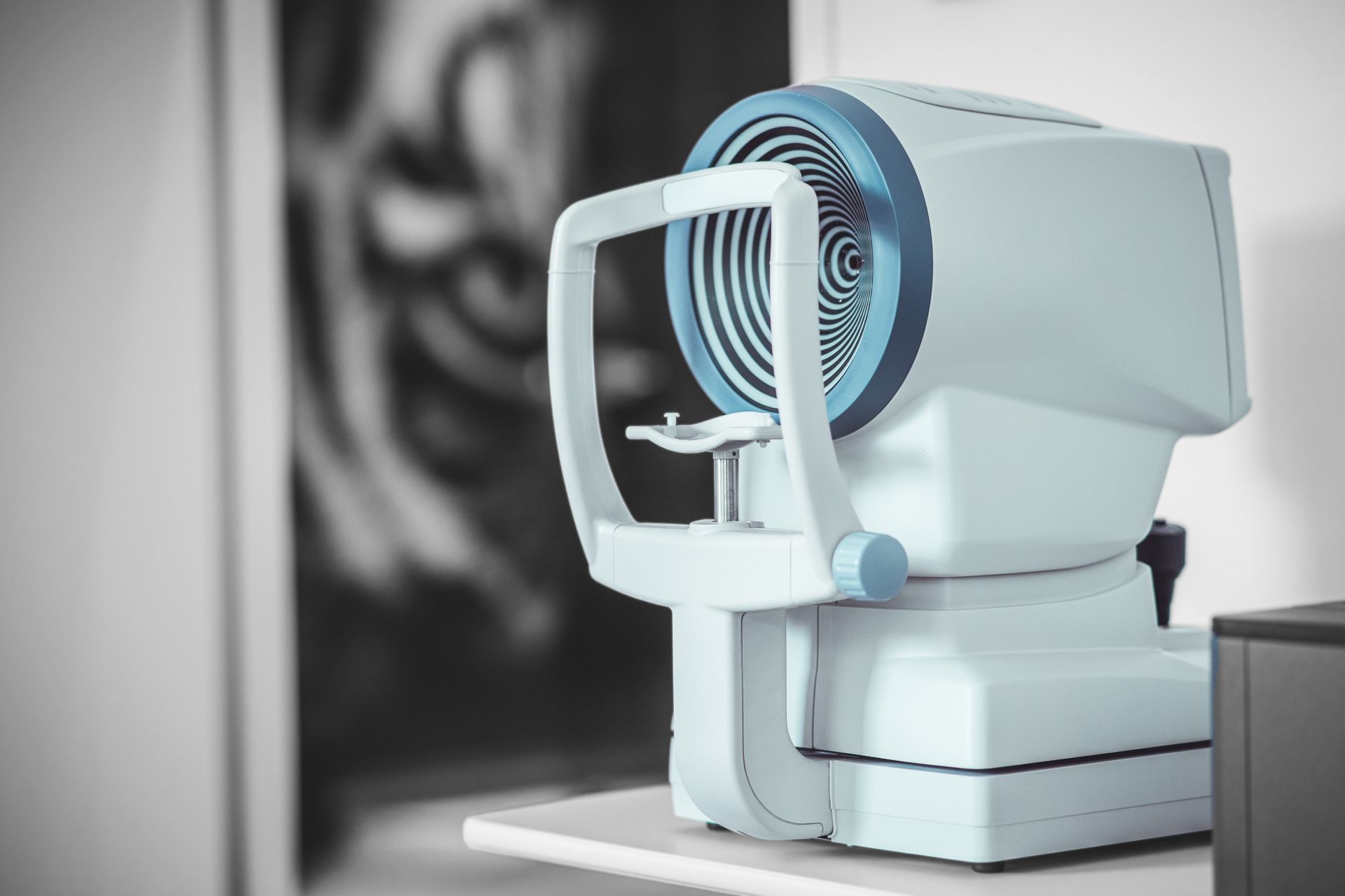 A machine is sitting on a table in front of a picture of a person 's face.