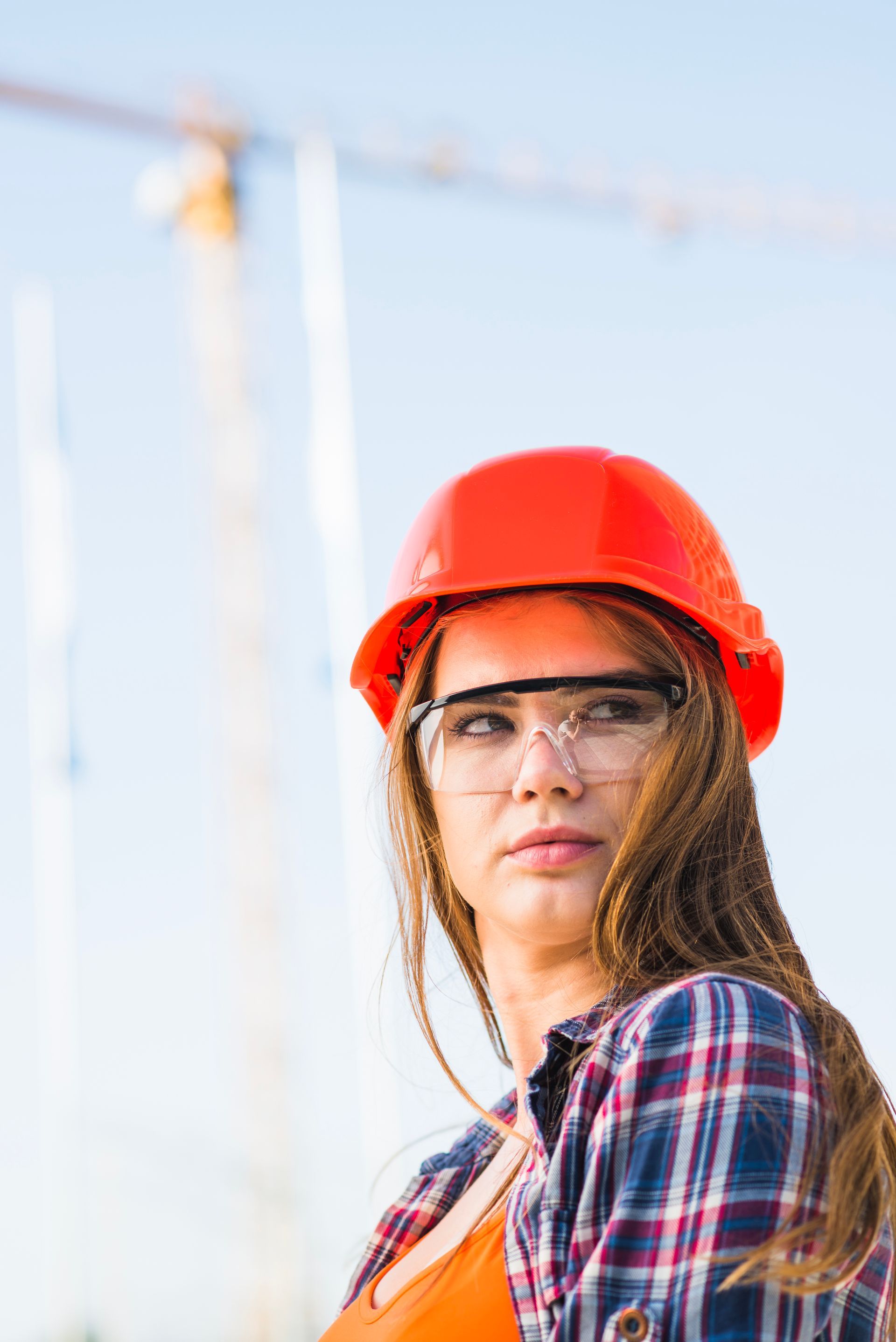 Construction worker wearing a red hard hat and safety glasses on a job site