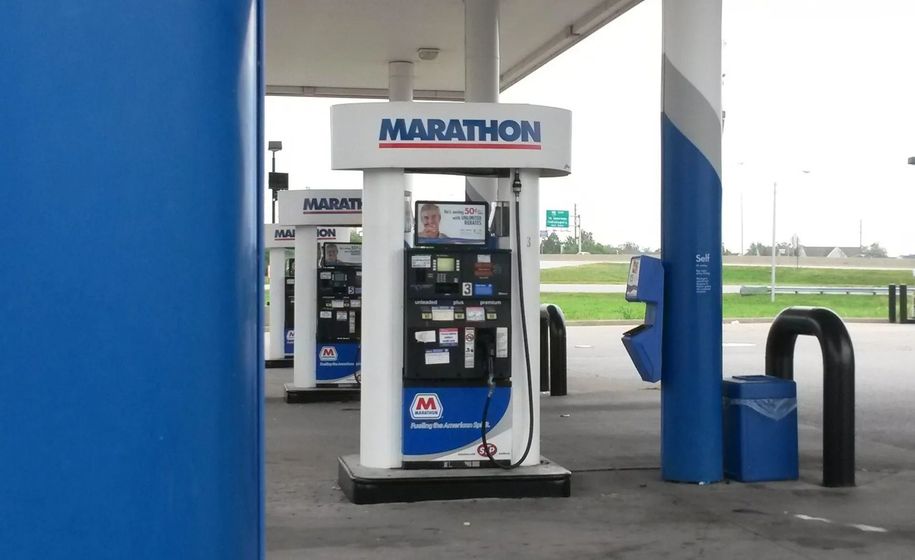 Marathon gas pump under a blue-and-white station canopy, with an open field in the background