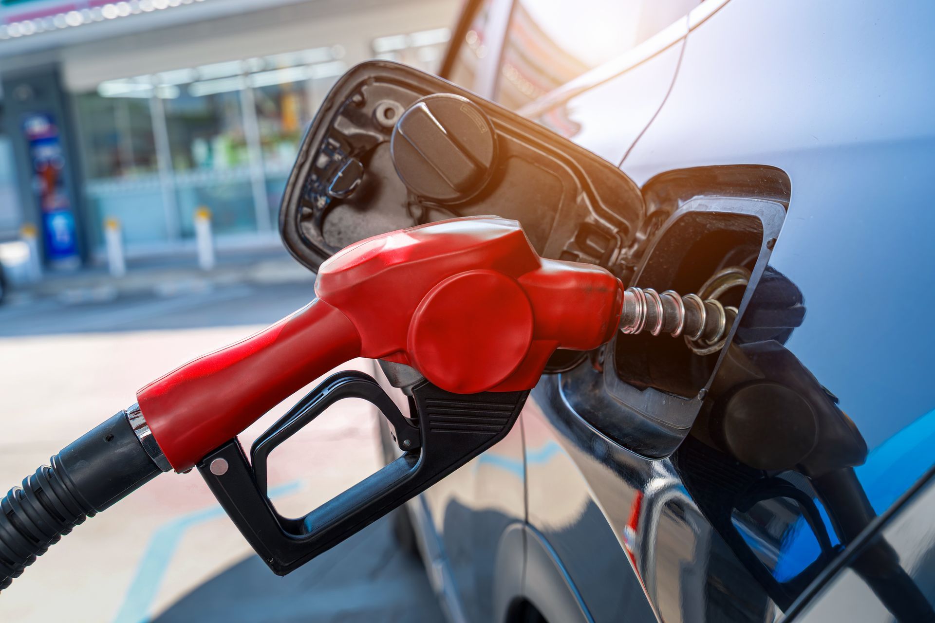 Red gasoline nozzle being inserted into a car at a gas station