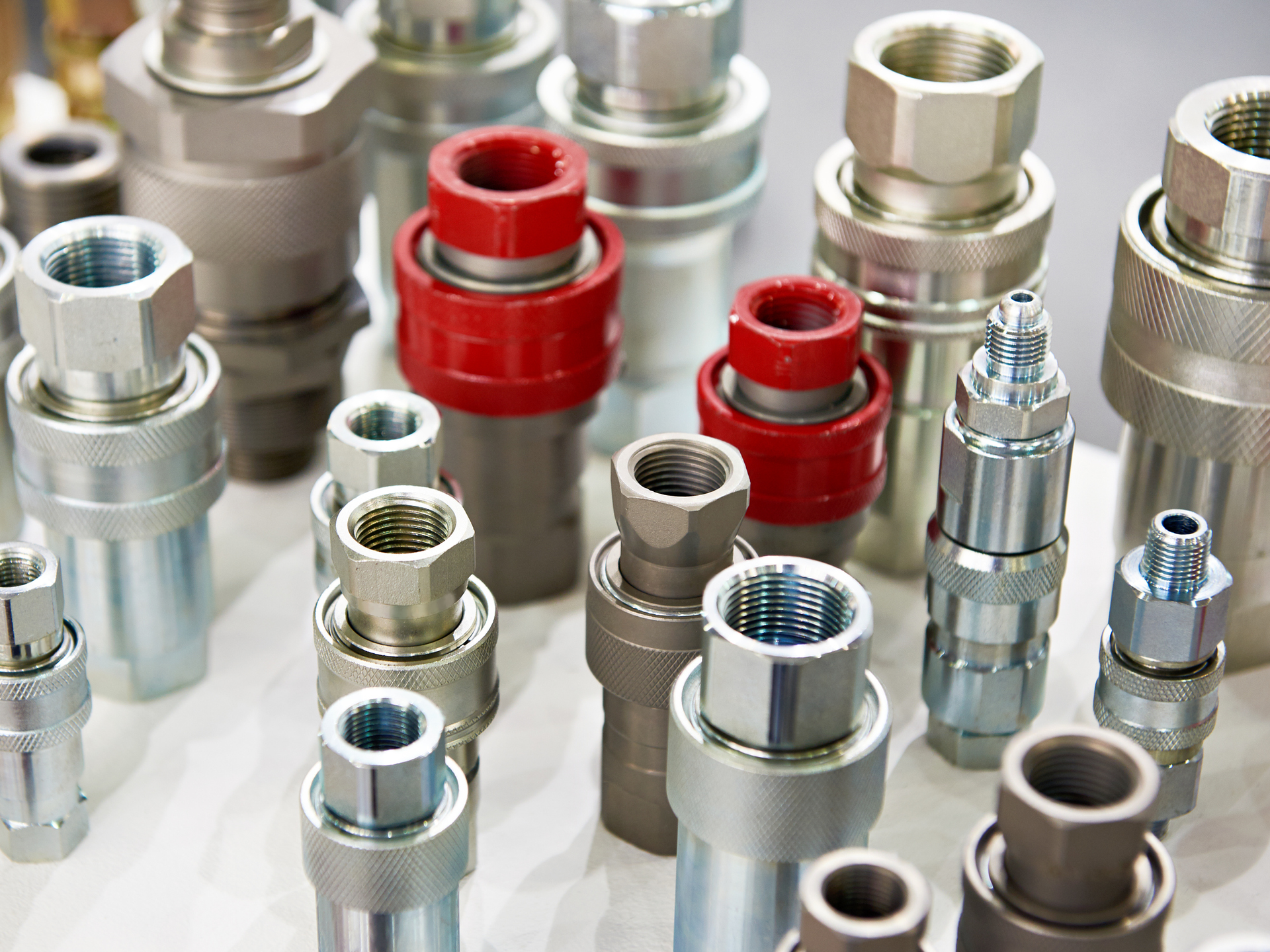 Close-up of various hydraulic quick-connect fittings, mostly silver, with a couple of red fittings on display.