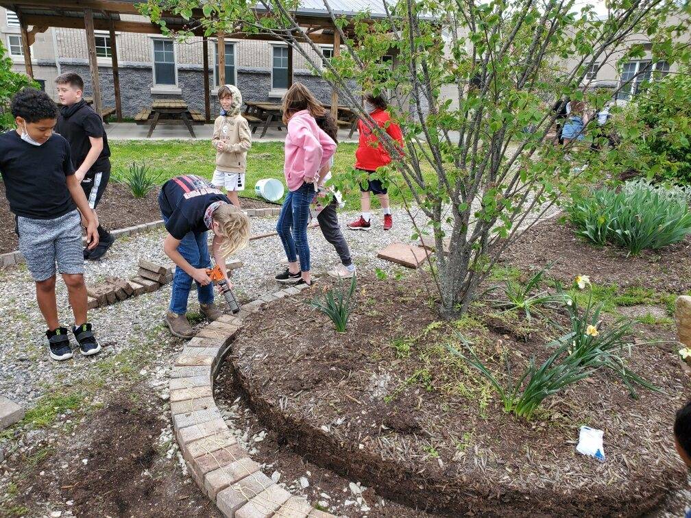 A group of children are working in a garden.