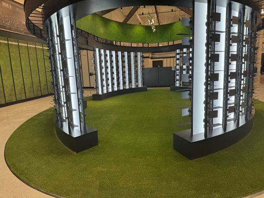 Circular display with eyewear on white panels, set in a grassy area. Black accents.