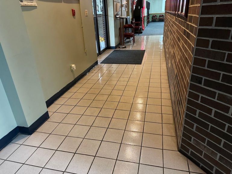 Hallway with light tile floor, brick wall on right, and a door at the end.
