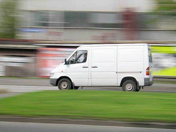A white van is driving down a city street.