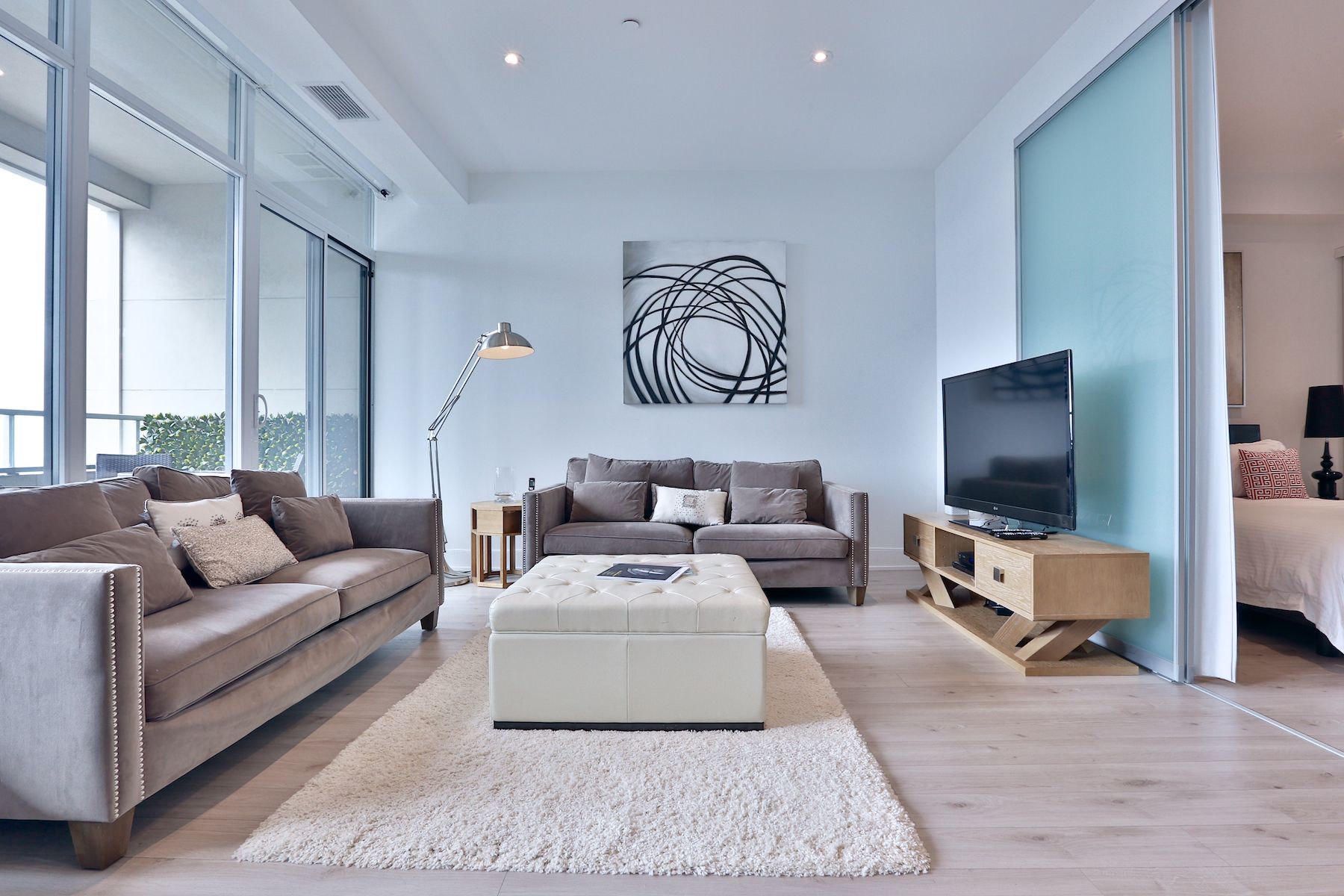 A living room with a couch , ottoman , coffee table and television.