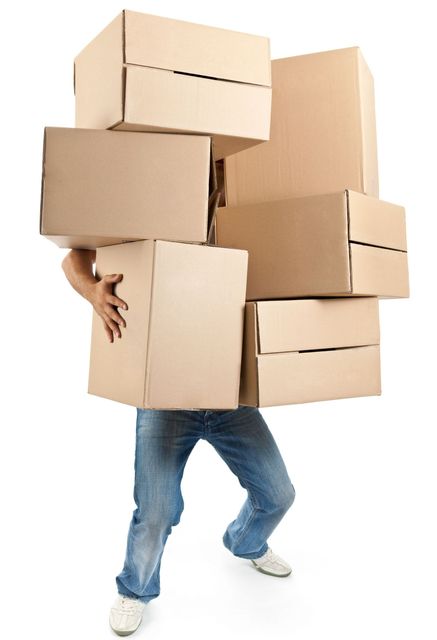 A man is carrying a stack of cardboard boxes on his back