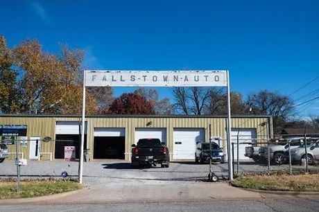 Fallbitton Auto repair shop with sign, garage bays, and vehicles. Bright blue sky and autumn trees.