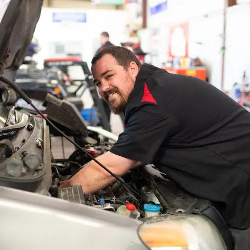 A man is working under the hood of a car.