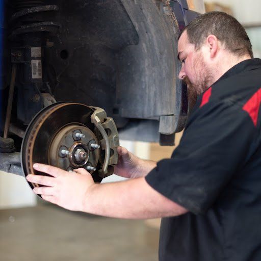 A man is working on the brake disc of a car