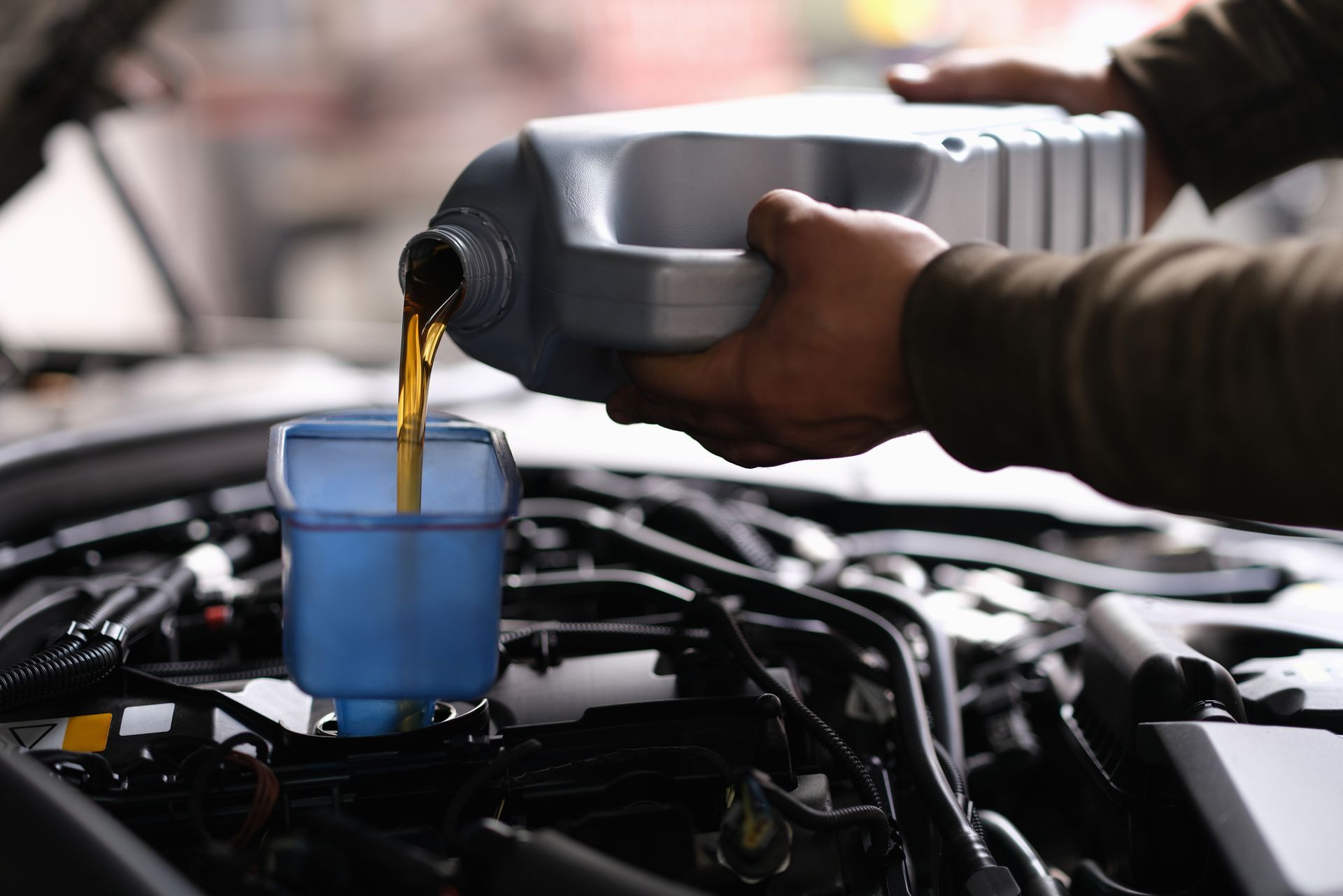 A person is pouring oil into a car engine.