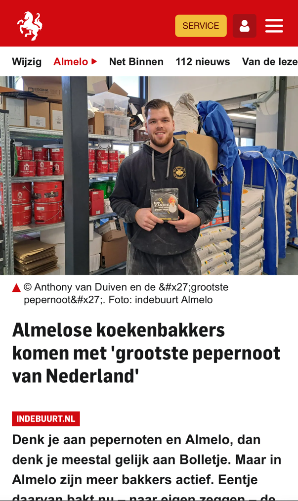 Medewerker Vondelkoeken, met een krantenkop over de grootste pepermolen uit Almelo.