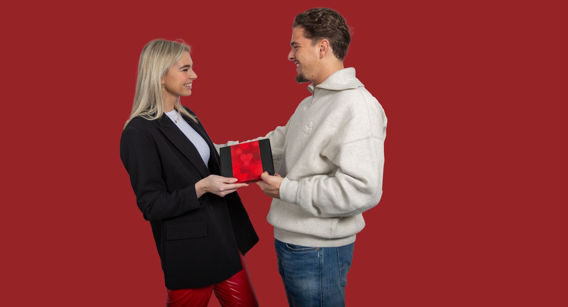 Een man geeft een vrouw een rood hart in een doos.